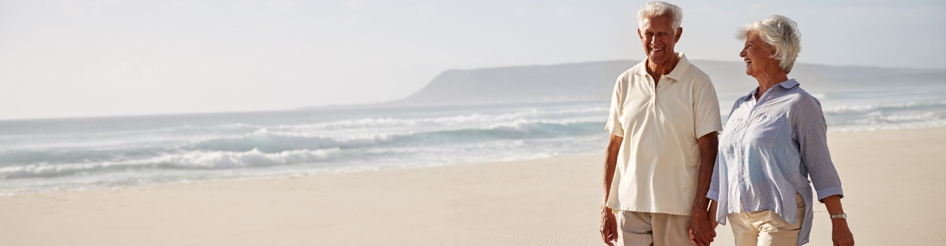 An elderly couple walking happily on the beach